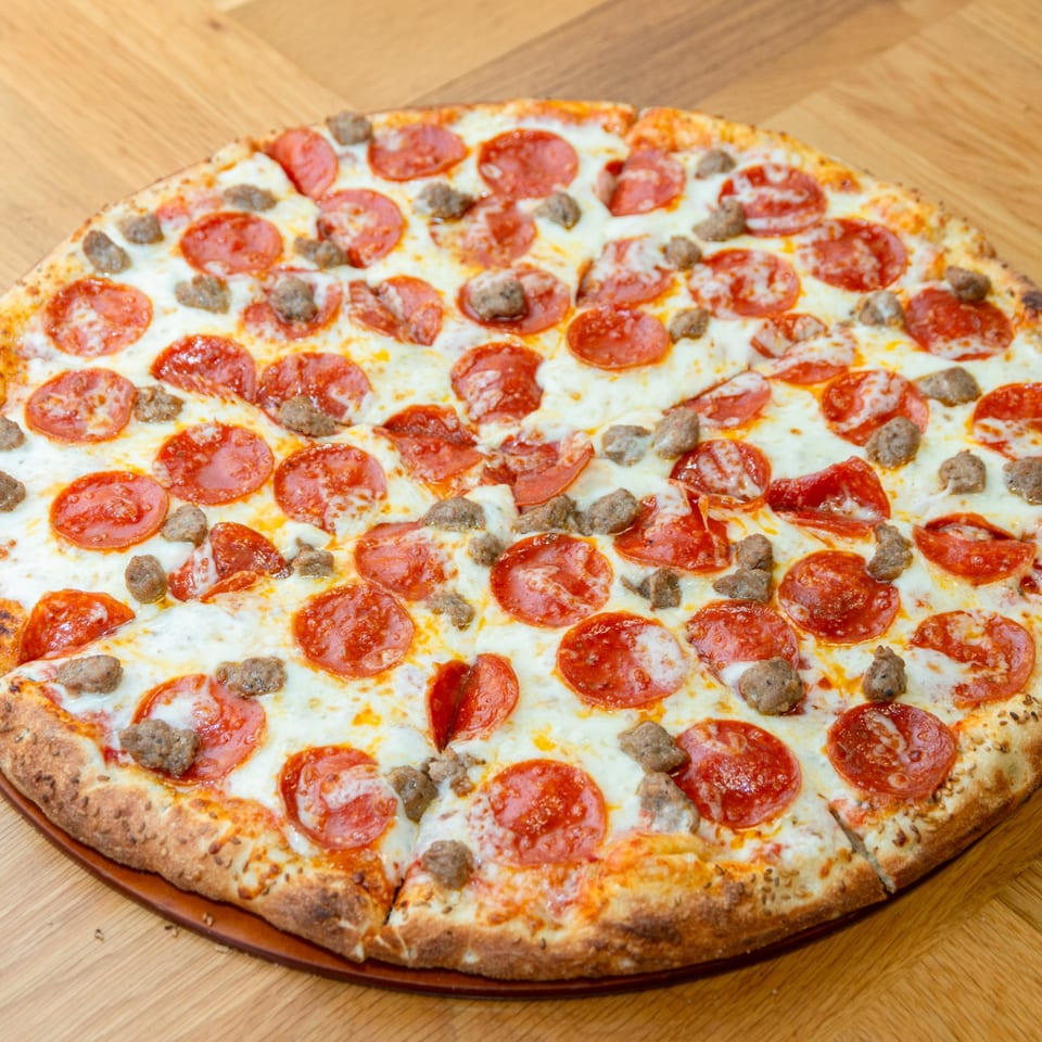 A Numero Uno Pizza with pepperoni and sausage toppings on a wooden table.